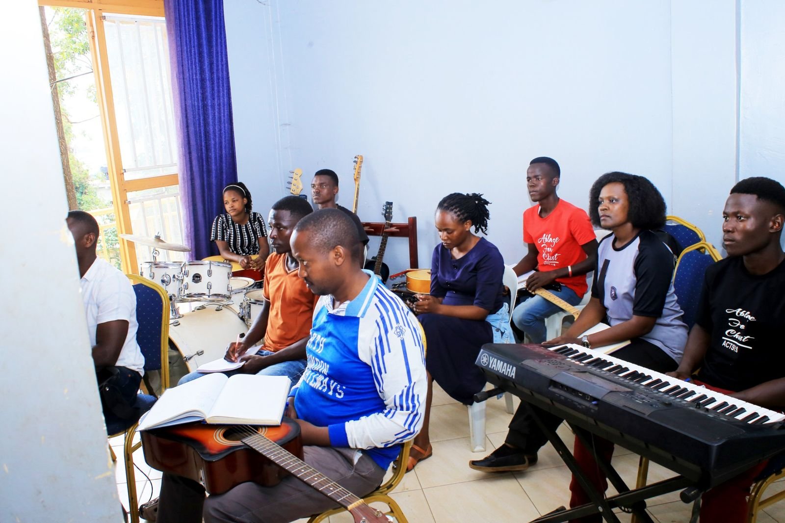 Music students in a class with keyboard, guitars and drums in Kampala