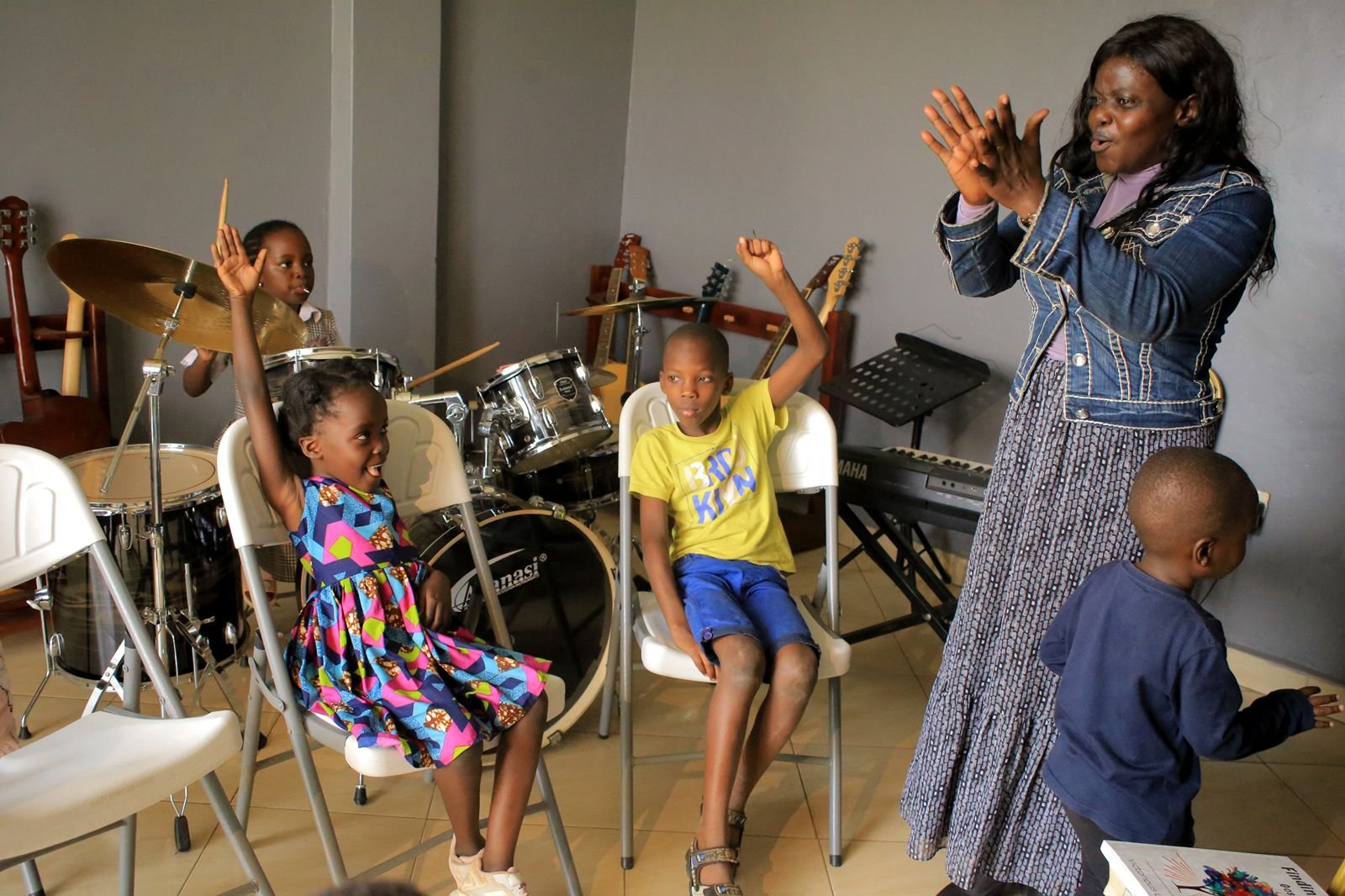 Children raising their hands in worship with their teacher